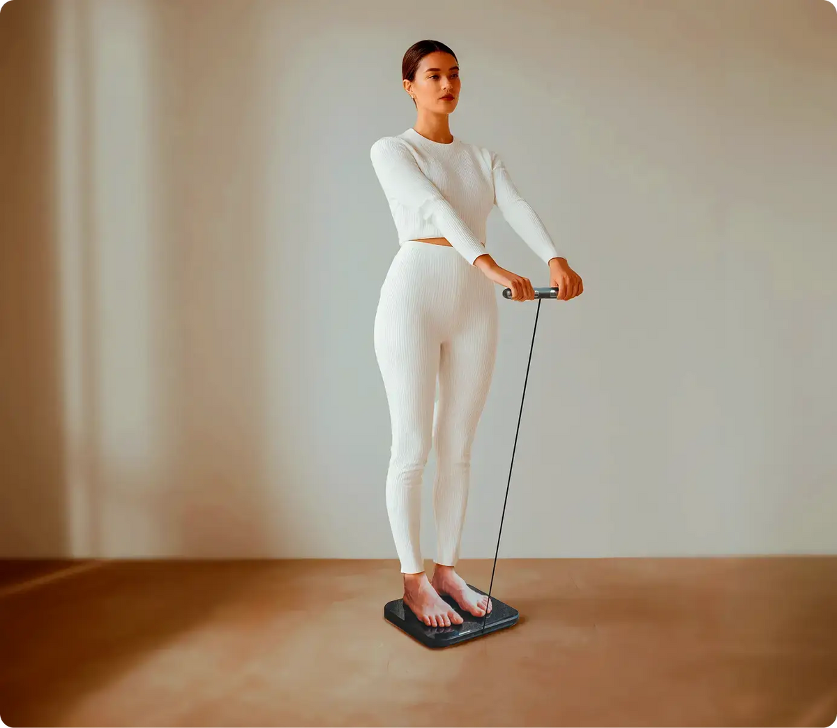 Woman standing on Hume Body Pod scale holding a handheld sensor, promoting advanced body insights and analysis with ‘Unlock the secrets to your body’ message.